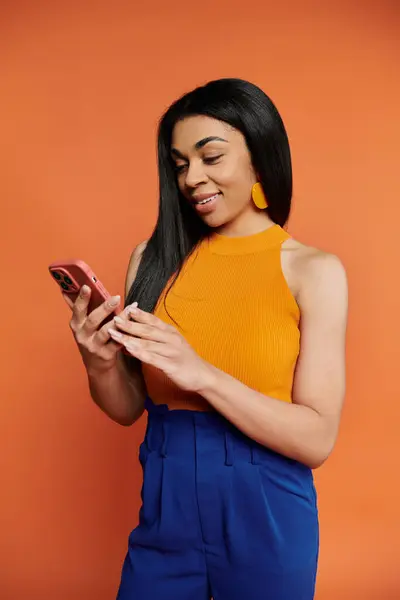 A stylish woman interacts with her smartphone, radiating confidence and joy. — Stock Photo