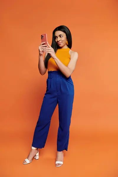 A joyful woman in vibrant attire interacts with her smartphone. — Stock Photo