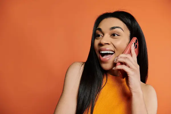Smiling and engaged, a woman chats happily on her smartphone. — Stock Photo