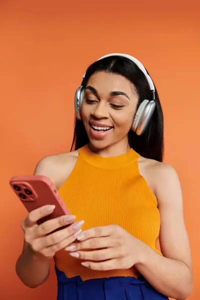 Mujer sonriente escucha música en los auriculares mientras se conecta con su teléfono inteligente. — Stock Photo