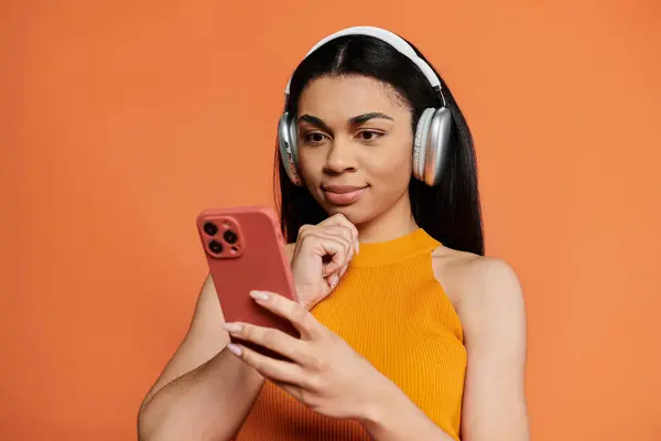 A young woman smiles while listening to music on her smartphone. — Stock Photo