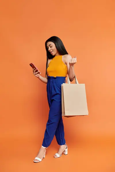 A fashionable woman checks her phone while carrying shopping bags. — Stock Photo