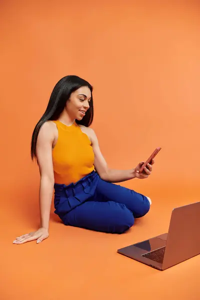 A woman seated on the floor curiously interacts with her smartphone. — Stock Photo