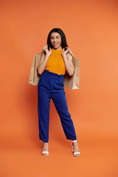 A vibrant young woman poses playfully with shopping bags. — Stock Photo