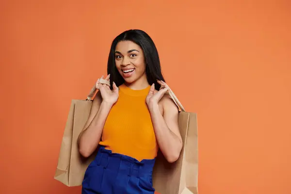 Una mujer alegre exhibe sus bolsas de la compra en una pose elegante. - foto de stock