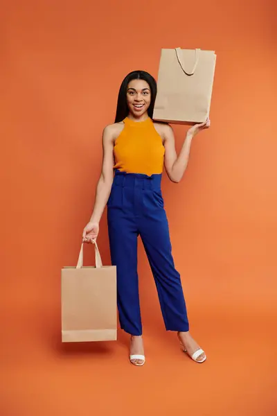 A cheerful woman holds shopping bags, radiating happiness and style. — Stock Photo
