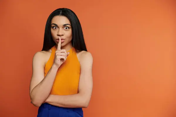 A confident woman expresses a playful silence with a finger to her lips. — Stock Photo