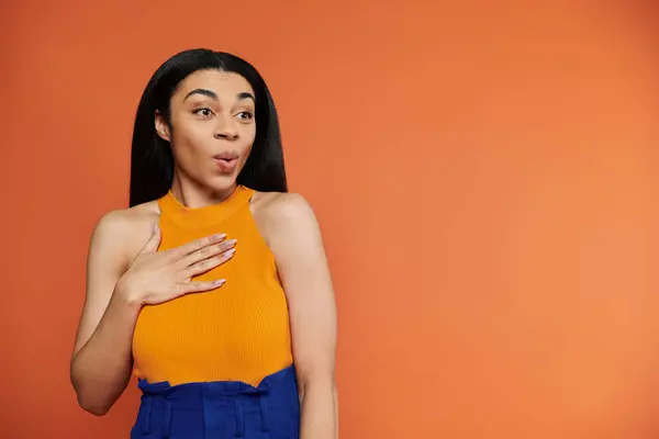 A stunning woman showcases a surprised expression with a hand on her chest. — Stock Photo