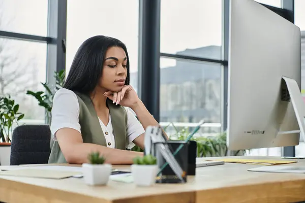 A thoughtful woman engages with her work at a modern office setting. — Stock Photo