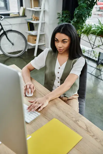 A woman works intently on her computer in a stylish office setting. — Stock Photo