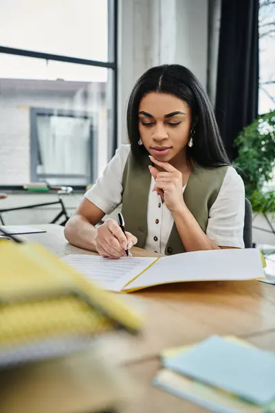 A young woman contemplates her thoughts while writing at a stylish desk. — Stock Photo