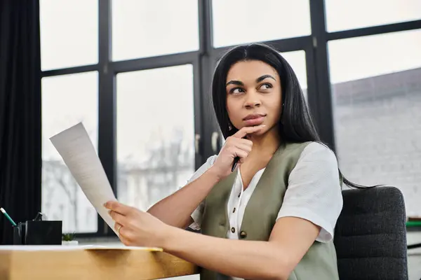 Pensive woman contemplates important documents at her workspace. — Stock Photo