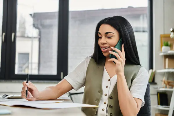 Smiling woman takes notes while talking on the phone in a stylish office. — Stock Photo