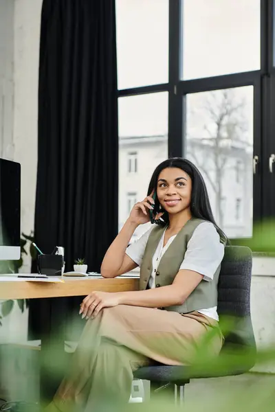 Una donna professionale alla moda parla sul suo telefono in uno spazio di lavoro contemporaneo. — Foto stock