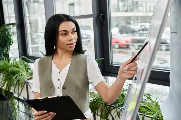 A confident woman presents ideas on a whiteboard in a stylish workspace. — Stock Photo