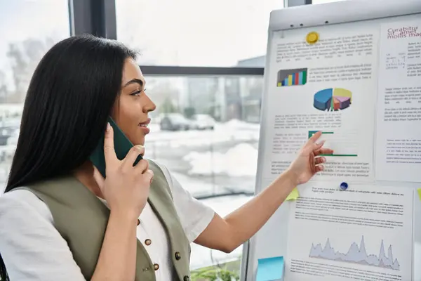 A woman discusses insights while pointing at a presentation in a modern workplace. — Stock Photo
