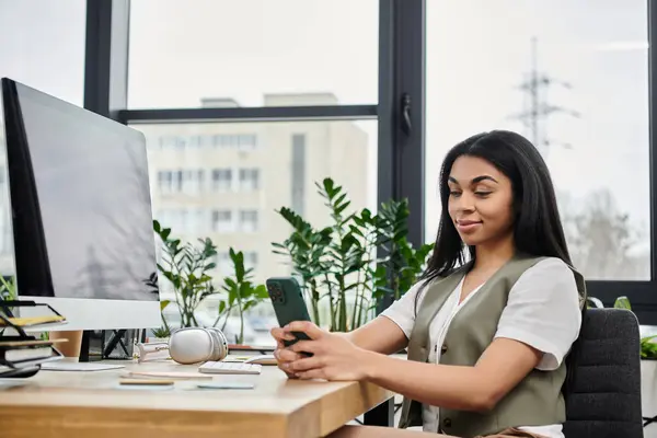 Smiling woman engrossed in her smartphone in a modern, plant filled workspace. — Stock Photo