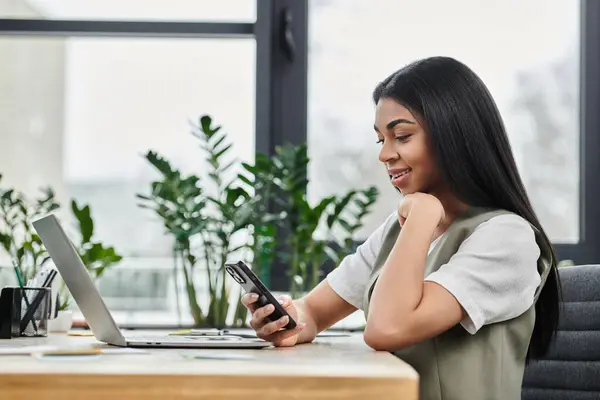 Mulher sorridente interage com seu telefone em um elegante escritório cheio de plantas. — Fotografia de Stock