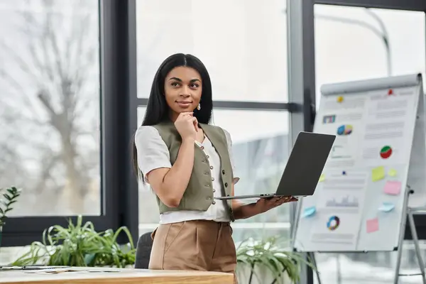 A confident woman contemplates with her laptop in a bright, stylish workspace. — Stock Photo