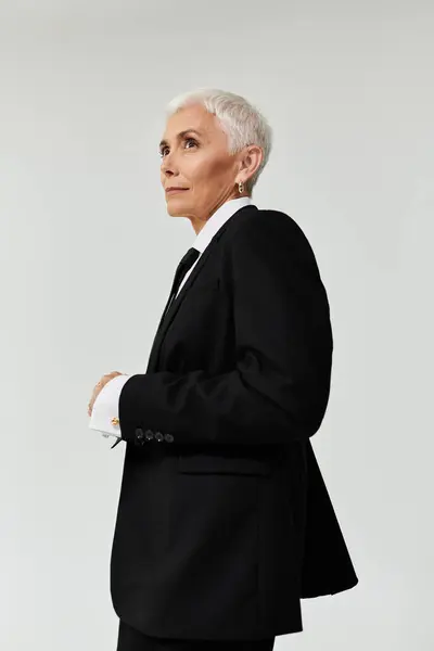 A mature woman with short hair exudes confidence in fashionable attire. — Stock Photo