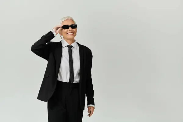 A confident woman in smart attire joyfully poses with sunglasses on. — Stock Photo