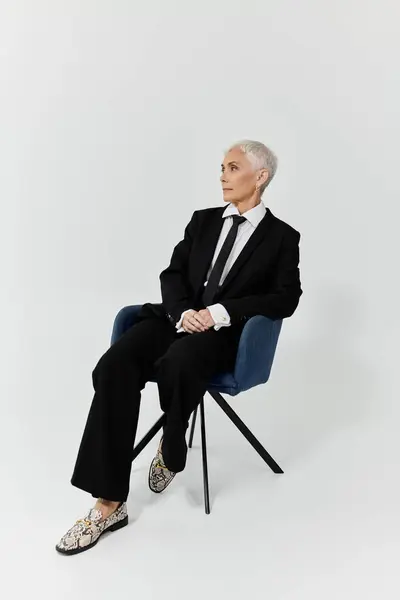 A mature woman exudes confidence in a tailored suit and bold footwear. — Stock Photo
