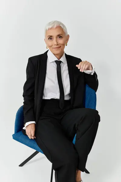 A mature woman exuding confidence in chic attire, seated with poise. — Stock Photo