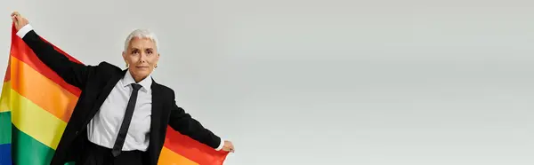 Confident woman showcases her pride in vibrant attire with a rainbow flag. — Stock Photo