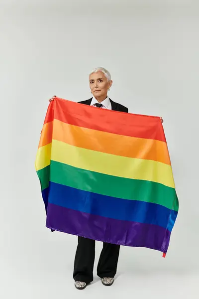 Une femme élégante arbore fièrement un drapeau arc-en-ciel, symbolisant l'amour et l'inclusion. — Photo de stock