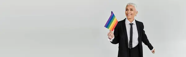 Confident woman joyfully waves rainbow flag, embracing her identity and style. — Stock Photo