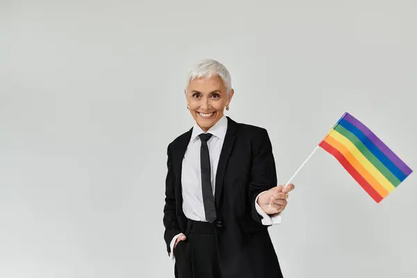 A stylish woman joyfully waves a rainbow flag, expressing her pride. — Stock Photo