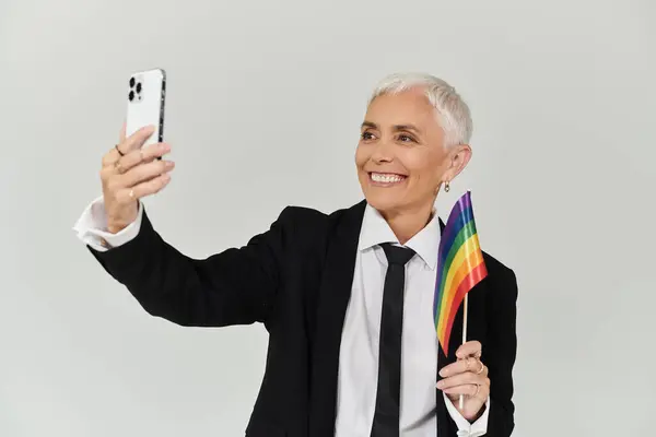 A stylish woman joyfully takes a selfie while holding a rainbow flag. — Stock Photo