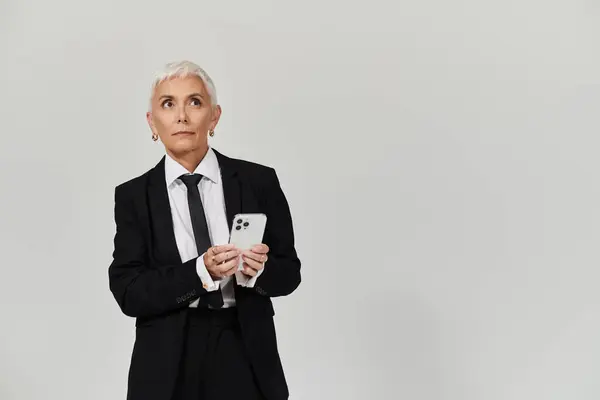 A mature beautiful woman with short hair showcases her fashion sense while texting. — Stock Photo