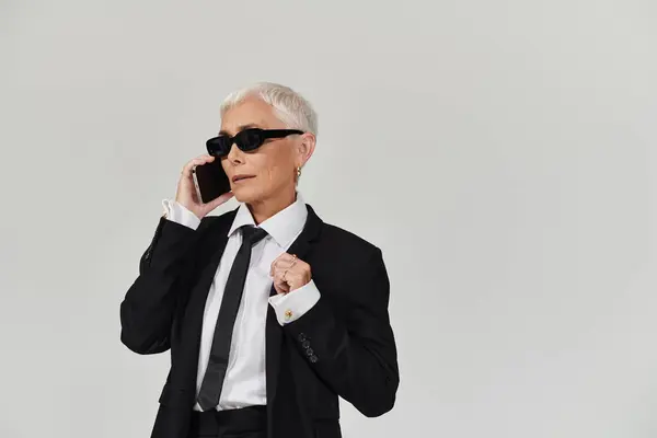 Chic woman with short hair makes a call, exuding confidence. — Stock Photo