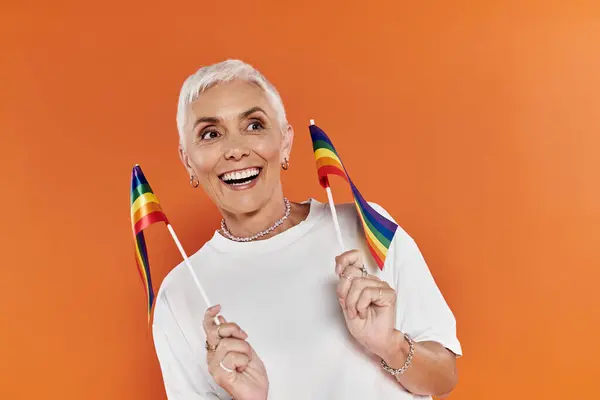 A joyful woman proudly waves rainbow flags, exuding confidence and pride. — Stock Photo