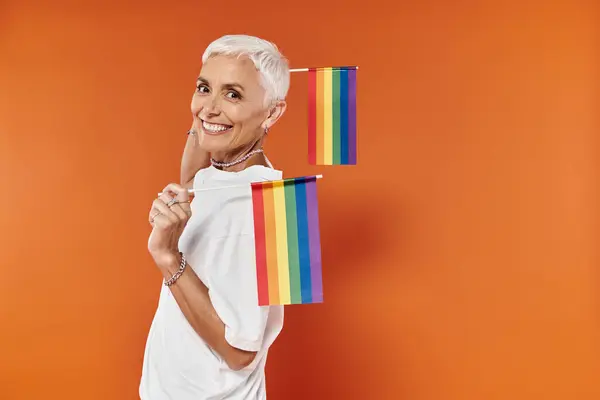 A confident woman joyfully shows her support for Pride, holding rainbow flags. — Stock Photo