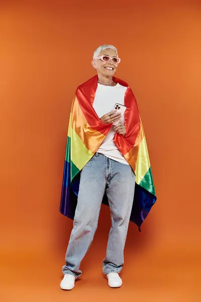 Mature woman proudly embraces her identity with a rainbow flag. — Stock Photo