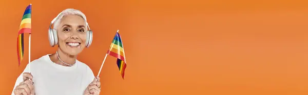 Cheerful woman proudly waving rainbow flags while listening to music. — Stock Photo