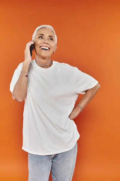 A stylish woman enjoys a cheerful phone conversation, exuding confidence and warmth. — Stock Photo