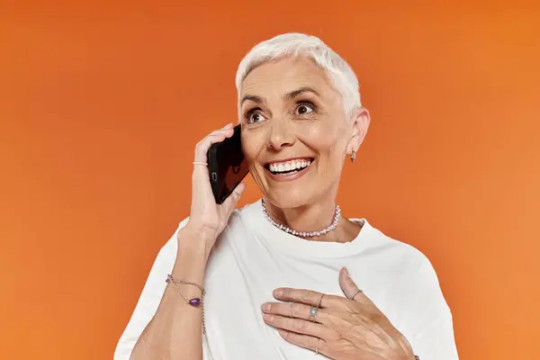 A joyful woman with short hair shares laughter during a phone call. — Stock Photo