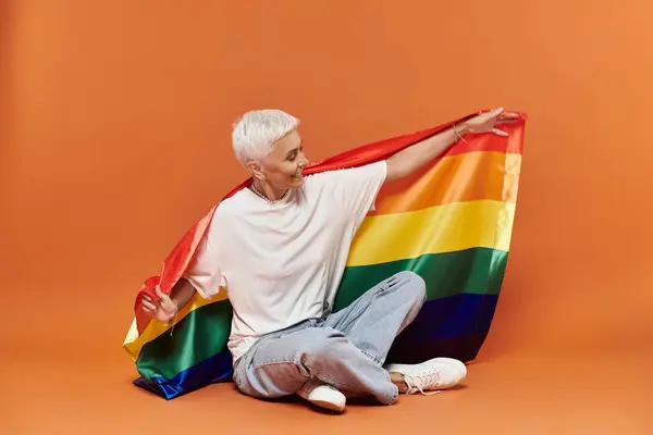 A mature woman embraces a rainbow flag with joy and confidence. — Stock Photo