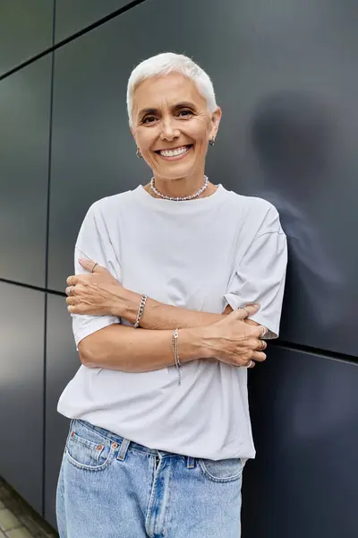 Eine reife Frau strahlt Freude aus, während sie in einem trendigen Outfit posiert. — Stockfoto