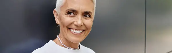 A mature woman with short hair beams with joy in her stylish outfit. — Stock Photo