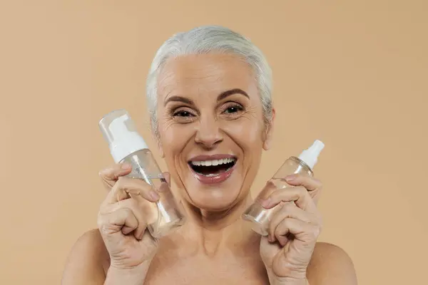A joyful woman showcasing skincare products. — Stock Photo