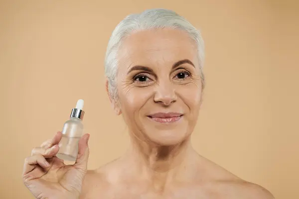 A mature woman with short hair holding serum bottle. — Stock Photo