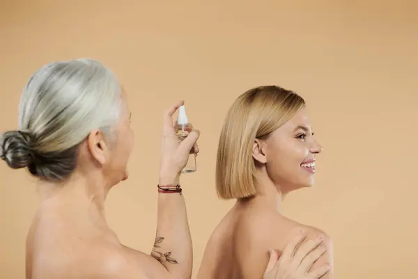 Uma mulher madura gentilmente spritzes cabelo de sua filha com cuidado e carinho. — Fotografia de Stock