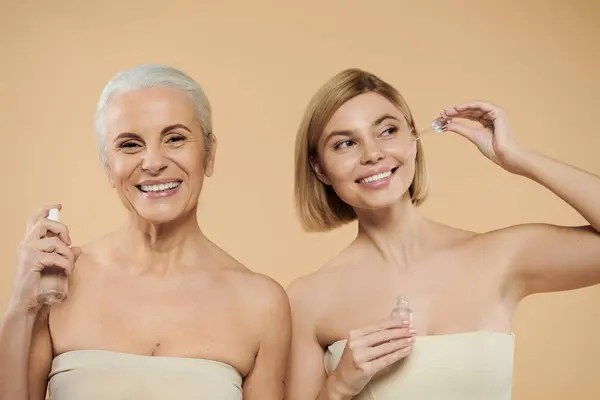 A mature woman and her daughter share smiles while enjoying their skincare routine. — Stock Photo
