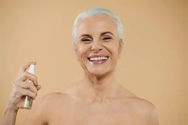 Une femme mûre utilisant joyeusement ses produits de beauté. — Photo de stock