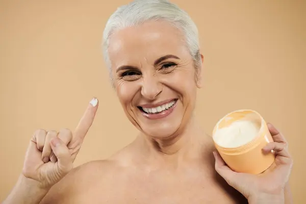 Mature woman with short hair using cream. — Stock Photo