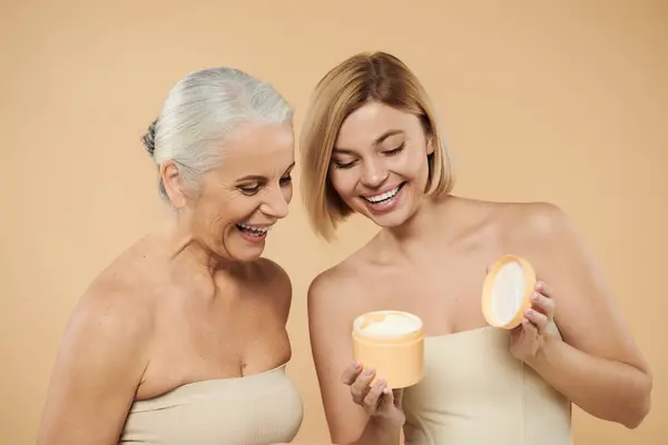 Uma mãe e filha riem enquanto exploram um produto de cuidados com a pele. — Fotografia de Stock